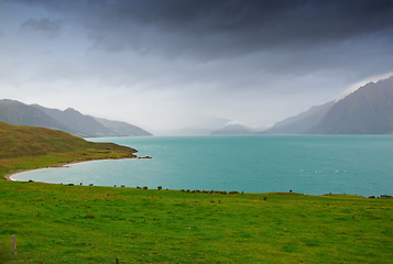 Image showing Lake, mountains and nature with view of green scenery on foggy or misty morning outdoor in spring. Earth, sky and water with grass on ground in natural ecosystem or environment of New Zealand