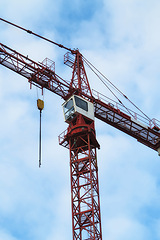 Image showing Crane, construction and blue sky background for building with heavy metal, steel or machinery outdoor. Hoist in city, urban or industrial development in a low angle of overhead equipment and tools