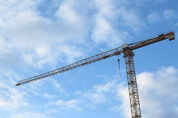 Image showing Crane, outdoor and clouds or blue sky background for building with heavy machinery or construction material. Hoist in city, urban or industrial development with low angle, tools or overhead equipment