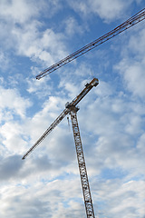 Image showing Crane, construction and clouds or blue sky background for building with heavy machinery or material outdoor. Hoist in city, urban or industrial development with low angle, tools or overhead equipment