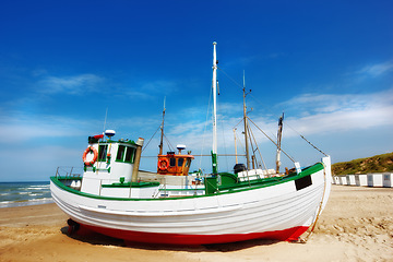 Image showing Beach, land and fishing boat on sand outdoor in nature by sea for travel in summer. Ship, transport and vessel on landscape, seashore or dock at harbor for sailing on journey by ocean in Australia