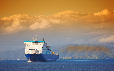 Image showing Ship, ocean and mountain at sunset to travel with clouds, water and transportation for vacation sailing. Cruise, sky and sea with yacht for tourism, holiday and adventure with sunrise, trip or nature