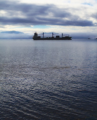 Image showing Ship, journey and travel at sea with cargo for transportation, international trade and logistics industry at sunset. Export, vessel and freight in ocean for sailing, shipping business and silhouette