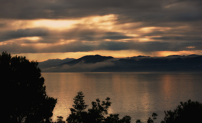 Image showing Landscape, silhouette and ocean on sunset background for environment, weather and travel or adventure. View of empty sea or water in nature with clouds, winter and sunset in Wellington, New Zealand