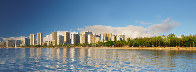 Image showing Ocean, city and buildings with landscape panorama, travel destination with skyscraper and outdoor. Urban development, architecture and environment for tourism, adventure and location with blue sky