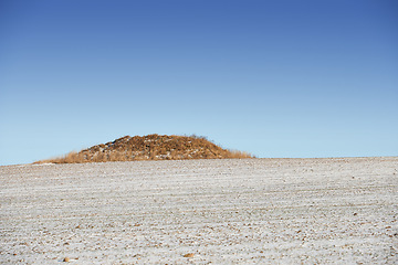 Image showing Desert, nature and landscape of environment with hill or countryside with grass, sand and blue sky. Mountain, peak and travel outdoor in summer to hillside with dry plants on dune, mound or bush