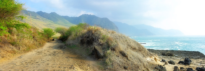 Image showing Trail, landscape and sky with ocean in nature for travel, adventure or hiking with mountain view in Hawaii. Pathway, gravel road or location with rocks, roadway or environment for holiday or vacation