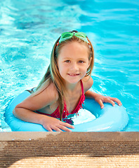 Image showing Happy, portrait and kid with inflatable in swimming pool, games or learning with support in water on vacation. Holiday, activity or girl relax at resort with toys in summer or child with fashion