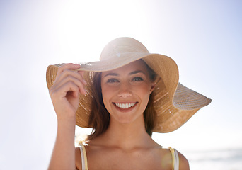 Image showing Woman, hat and portrait for smile at beach for holiday or getaway on weekend in sunlight for summer. Cheerful and happy person with hand and face in warm weather for outdoor on trip or vacation