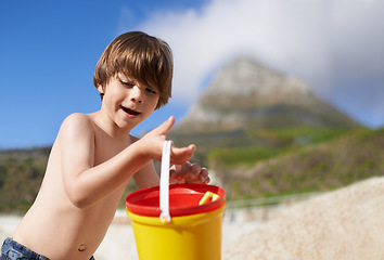 Image showing Happy, beach and child with bucket and toys on summer holiday, vacation and relax by ocean. Childhood, building sand castle and young boy playing for adventure, fun and weekend by seaside in nature