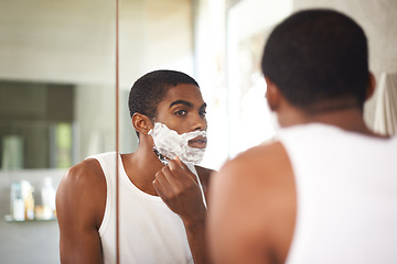 Image showing Black man, mirror and shaving with razor in bathroom for grooming, skincare or morning routine. Reflection, beard or person with cream on face for cleaning, health or hair removal for hygiene in home