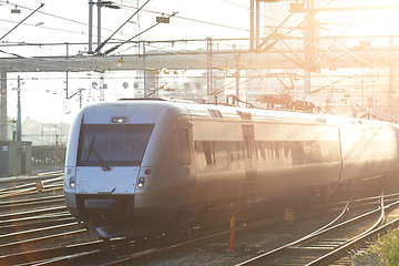 Image showing Train, station and tracks outdoor for travel, commute and journey or transportation in morning sunshine. Subway, infrastructure and railway or railroad for public service, tourism and city technology