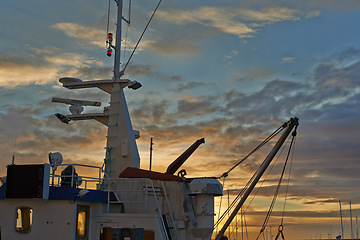 Image showing Ship, sunset and harbor at sea to travel with closeup, clouds and transportation for vacation sailing. Ship, dock and ocean with yacht for tourism, holiday and adventure with sunrise, sky and nature