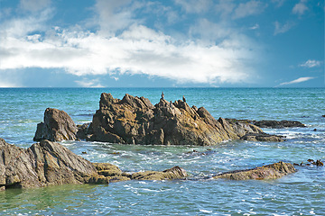 Image showing Rocks, sea and waves, landscape in nature with blue sky and clouds, coastline and outdoor travel destination. Surf, Earth and water with ocean view, natural background and beach location in Cape Town