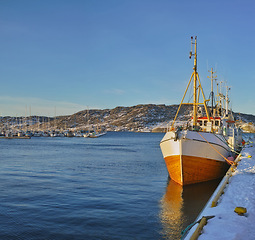 Image showing Boat, water and dock at sea to travel with blue sky, mountain and transportation for vacation sailing. Ship, harbour and ocean with vessel for tourism, holiday and adventure with landscape and nature