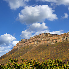 Image showing Mountains, environment and blue sky with nature, clouds and sunshine with landscape and adventure. Empty, rock and grass with flowers or countryside with summer and travel with vacation or plants