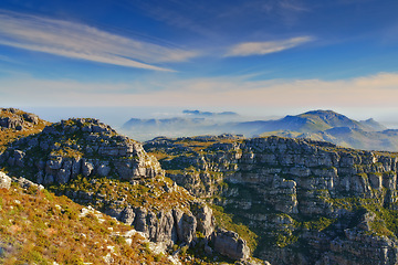 Image showing Mountains, blue sky and natural landscape with clouds, cliff and calm location for travel destination. Nature, fog and sustainable environment with earth, peace and holiday with sunset on horizon.