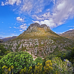 Image showing Mountains, summer and blue sky with nature, clouds or stone with landscape or plants with sunshine. Empty, outdoor or grass with flowers or countryside with adventure or travel with vacation or earth