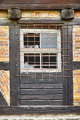 Image showing Old, broken window and exterior with cage or brick wall of abandoned house, building or wooden frame. Historic outdoor bunker of rubble, glass crack or damage from war wreck, destruction or vandalism