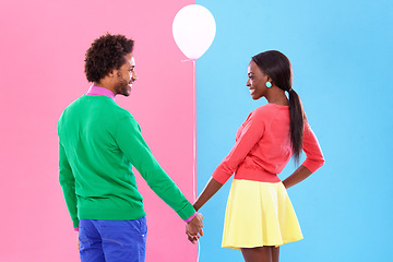 Image showing Happy, couple and holding hands with balloon in studio for gender reveal on pink and blue background with fashion. Back, woman and man excited together with support in pregnancy, news or announcement