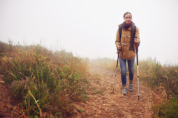 Image showing Woman, hiking and field with trekking sticks, winter and support for fog trail in mountain. Athlete, backpack and outdoor gear for safety in sustainable environment, slippery and walking for fitness