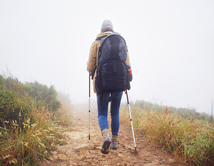 Image showing Person, hiking and back in nature with trekking sticks, winter and support for fog trail in mountain. Athlete, backpack and sport gear for safety in wet environment, slippery and walking for fitness