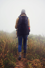 Image showing Person, hiking and back in countryside for trekking, sticks and support for fog trail in mountain. Athlete, backpack and sport gear for safety in cold environment, slippery and walking for fitness