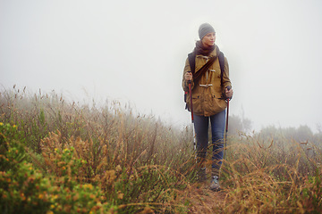 Image showing Woman, hiking and thinking in countryside for trekking, sticks and planning by fog trail in mountain. Athlete, backpack and sport gear for safety in cold environment, idea and walking for fitness