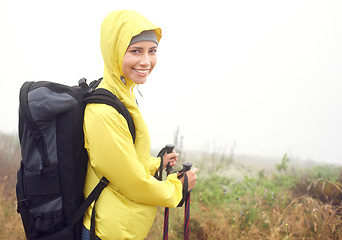 Image showing Portrait, woman hiker and smile on mountain trail, exercise and cardio for fitness in nature. Fog, walking stick and gear for training and morning overcast weather, workout and happy or rest on path