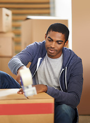 Image showing Home, moving and man packing boxes, shipping and real estate with new property and machine. African person, apartment and guy with a tool for tape and cardboard with package and parcel in a lounge