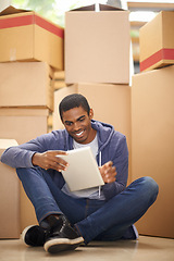 Image showing Boxes, home and black man with a tablet, smile and typing with internet and package in lounge. African person on the floor, apartment and guy with tech or cardboard with communication and digital app