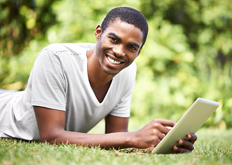 Image showing Portrait, smile and tablet with black man on grass of garden for research or information in summer. Technology, internet and ebook with happy young person lying on green field outdoor in backyard