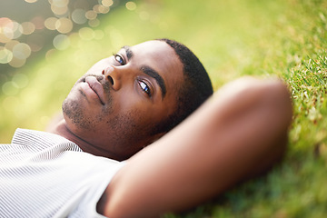 Image showing Portrait, serious and black man on grass in garden of summer park for peace, wellness or mindfulness. Relax, nature and field with confident young person lying on ground for break, chill or rest