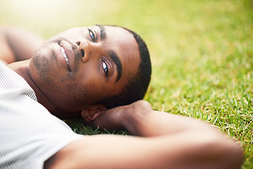 Image showing Portrait, relax and black man on grass in garden of summer home for peace, wellness or mindfulness. Face, nature and field with happy young person lying on green ground from above for break or rest