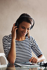 Image showing Woman, home and office with tablet, headphones and listening to podcast while working on touchscreen for freelance job. Female person, internet or online with headset for communication or consulting.