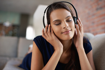 Image showing Face, music and relax with woman on sofa in living room of home to smile for free time break. Headphones, peace and radio with young person lying on couch in apartment for weekend chilling or rest