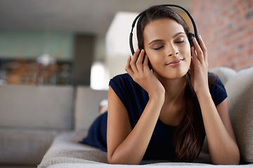 Image showing Face, music and peace with woman on sofa in living room of home to relax for free time break. Headphones, radio and audio with young person lying on couch in apartment for weekend chilling or rest