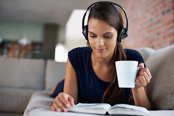 Image showing Book, coffee and music with woman on sofa in living room of home, reading to relax at weekend. Storytelling, headphones and drinking tea with young person in apartment for hobby, leisure or time off