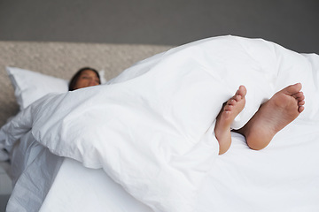 Image showing Tired, feet and woman in bed sleeping, home and white duvet for bedding , lazy and exhausted. Morning, bedroom and female person on day off to relax in apartment, rest and cosy with blanket and dream