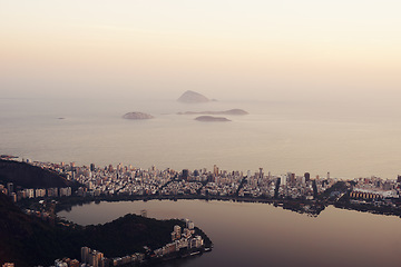 Image showing Drone, city and landscape at sunset with ocean, coast or water in background in urban Rio de Janeiro. Brazil, lagoon and cityscape with mountain on holiday for travel on vacation with sea on horizon