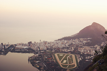 Image showing Mountain, city and landscape at sunset with ocean or stadium from drone in urban Cape Town. Cityscape, aerial view and calm skyline with hill on holiday or travel on vacation with sea on horizon