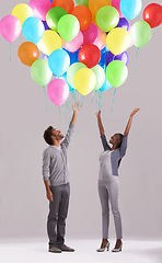 Image showing Happy couple, party and celebration with balloons for event, birthday or romance on a gray studio background. Excited man and woman with colorful blowups of helium for date, giveaway or anniversary