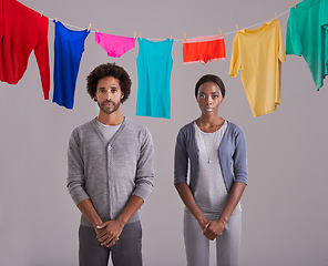 Image showing Portrait, people and laundry in studio with clothes, hanging and drying on washing line. Black person, man and woman in marriage or dating, cleaning and routine while standing on gray background