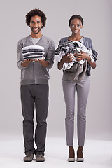 Image showing People, studio and pile of washing in hand for wash, laundry day and couple cleaning together. Happy, man and neat clothes folded with woman, messy and unhappy for dirty wardrobe on gray background