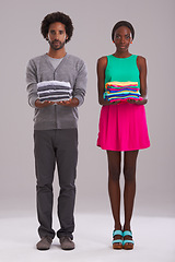 Image showing Portrait, couple and folded clothes for laundry, fashion and cleaning in studio isolated on a gray background. African man, serious woman and fabric for housework, housekeeping or chores together