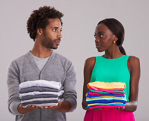 Image showing Couple, folded clothes and laundry in studio for chores, domestic and housework together. Black people, man and woman in relationship or married are organizing, color code shirts on gray background