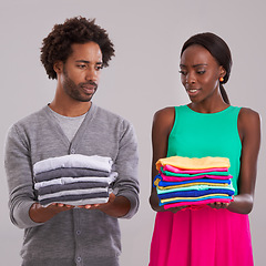 Image showing People, studio and pile of laundry in hand for neat, wash day or cleaning clothes together. Couple, thinking and unsure of color choice for wardrobe with fashion, uncertain or ocd on grey background