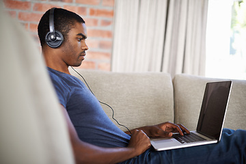 Image showing Man, internet and music with laptop on sofa for movie streaming, podcast and online games with listening. Young, black person and technology with headphones for relax, studying and learning in lounge