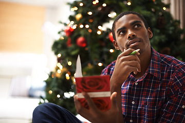 Image showing African, man and thinking for christmas, card and holiday with message for vacation. Person, pen and idea for writing, home and tree with decorations, communication and creative at home for gift