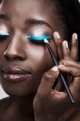 Image showing Brush, makeup and face of black woman with cosmetics for wellness, beauty and model. Cosmetology, skincare and person with tools for makeover application, blue eyeshadow and products in studio